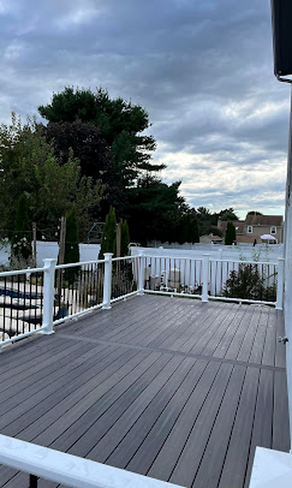 New composite deck with white railing at evening, built by 1 All American Roofing LLC in NJ